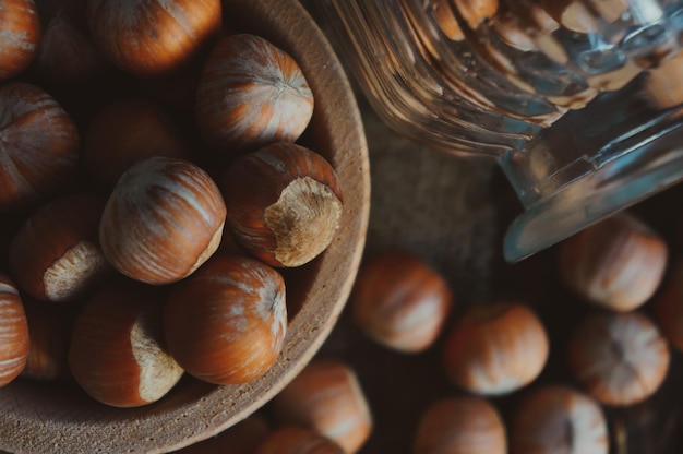 Nature morte aux noisettes et noisettes entières sur une vieille table en bois rustique avec une cuillère et un bol de bois avec place pour votre texte