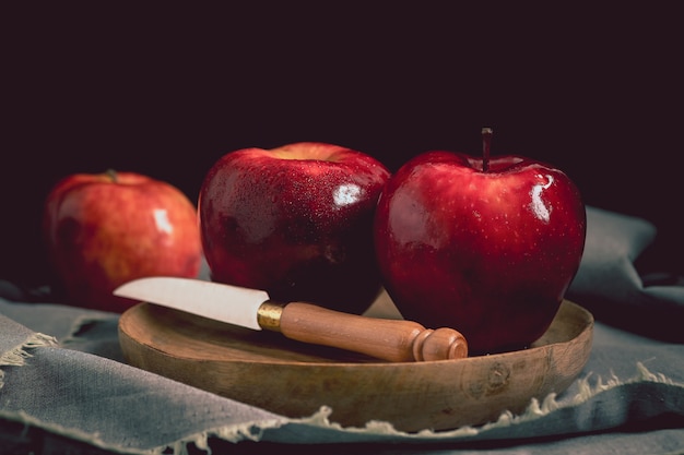 Photo nature morte aux pommes red delicious et un couteau sur une plaque en bois