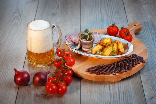 Nature morte avec bière, hareng, charcuterie, tomates cerises, pommes de terre champêtres