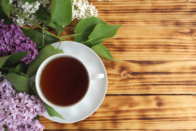 Photo nature morte, un bouquet de beaux lilas frais avec une tasse de thé tôt le matin. un beau bouquet est sur la table. place pour votre texte.