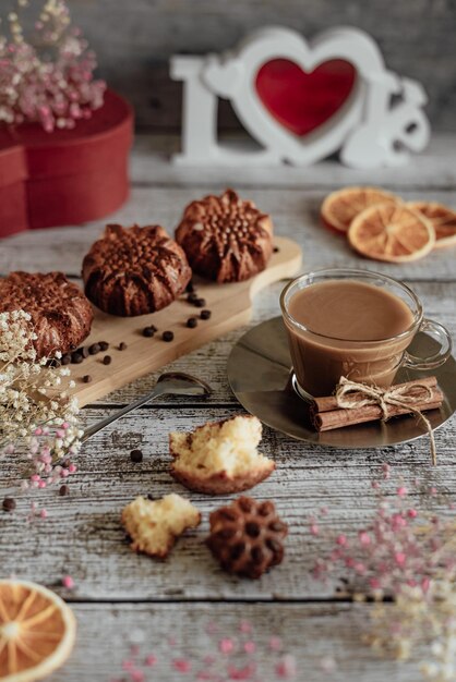 Photo nature morte café cappuccino et cupcakes sur un support sur une carte postale de fond en bois clair pour les vacances