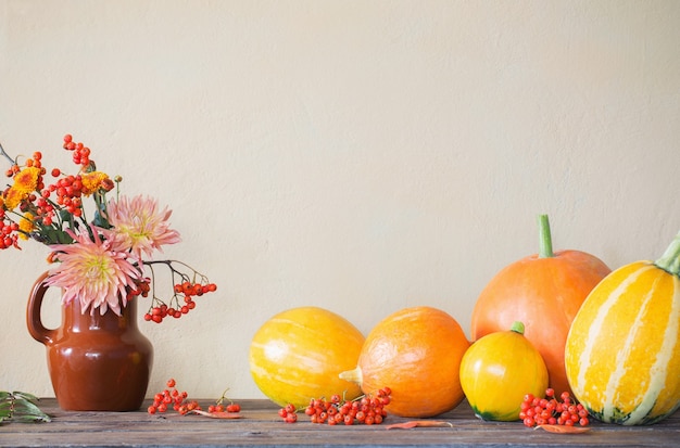 Nature morte avec des citrouilles et des branches de rowan sur table en bois