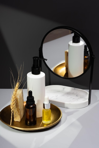 Nature morte créative avec des cosmétiques bio Ensemble d'huiles essentielles savon artisanal et miroir sur fond gris foncé Le concept de soins personnels et de produits biologiques Réflexion dans le miroir