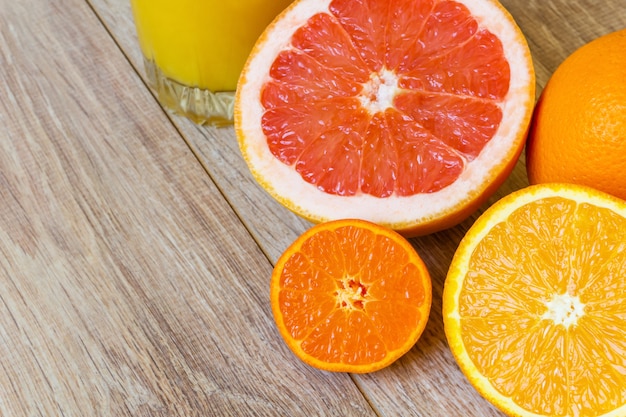 Nature morte - divers agrumes entiers et coupés et verre de jus d'orange sur une table en bois