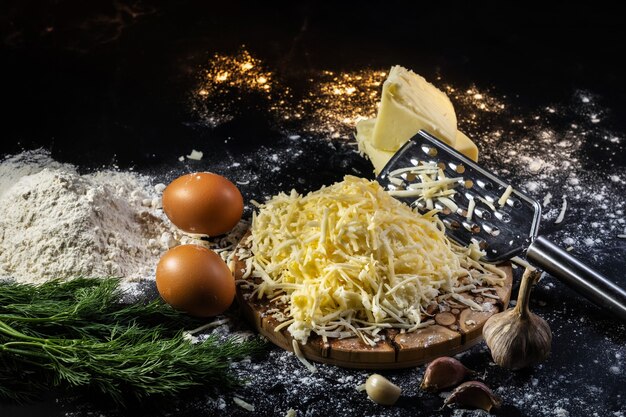 Nature morte du processus de fabrication de boules de fromage avec de l'ail et de l'aneth sur une surface noire.