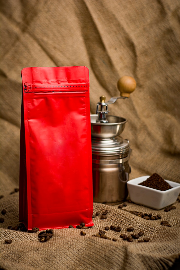 Photo nature morte d'emballages de café sans marque dans différentes couleurs et arrière-plans naturels à côté de tasses de cafetière et de café