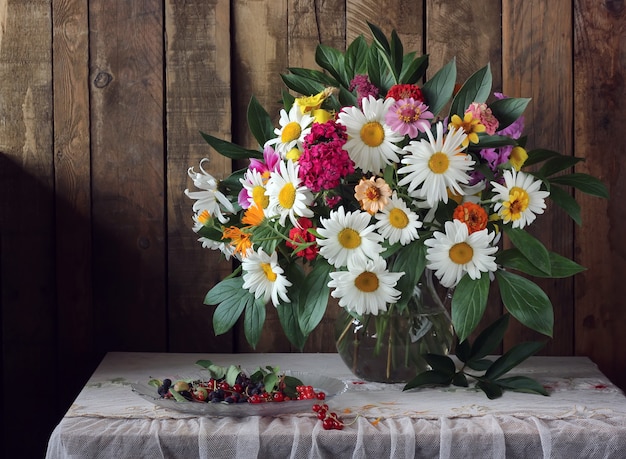 Nature morte d&#39;été avec un bouquet et des baies sur la table avec une nappe