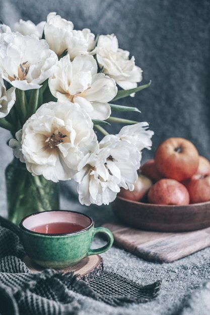 Photo nature morte fleurs dans un vase tulipes et pommes rouges sur une assiette