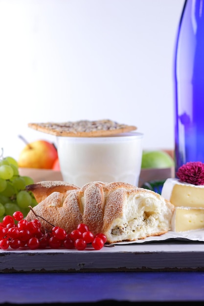 Nature morte de fromage miel noix fruits et une bouteille bleue sur un arrière-plan flou Nourriture pour une collation saine et savoureuse sur un parchemin blanc Gros plan