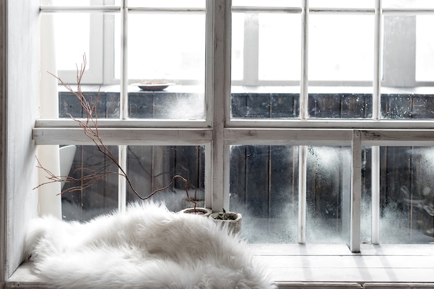 Nature morte d'hiver confortable. Plantes en pots et fourrure chaude sur rebord de fenêtre vintage. Saison d'hiver, passer l'hiver au concept de maison confortable.