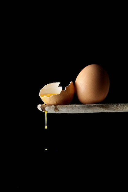 nature morte d'humeur noire avec une cuillère en bois et un œuf entier avec une moitié de jaune et un album descendant