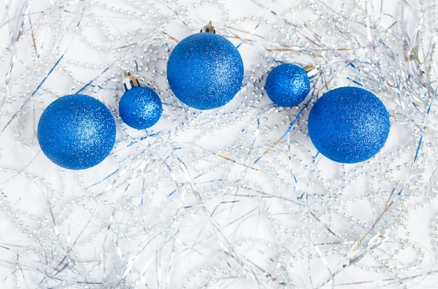 Photo nature morte de noël sur un blanc, y compris des décorations de noël bleues et des guirlandes et des perles d'argent.