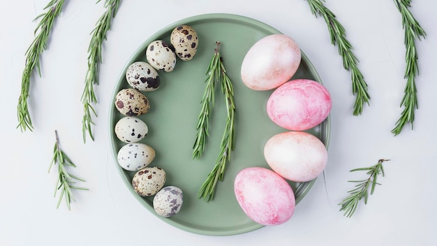 Nature morte de Pâques, oeufs colorés peints et oeufs de caille couchés dans un bol sur fond gris