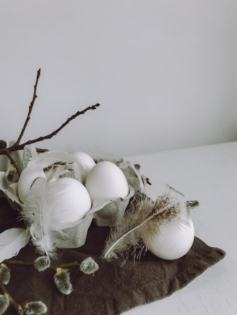 Nature morte de Pâques rurale élégante Oeufs naturels plumes branches de saule sur tissu sur table rustique