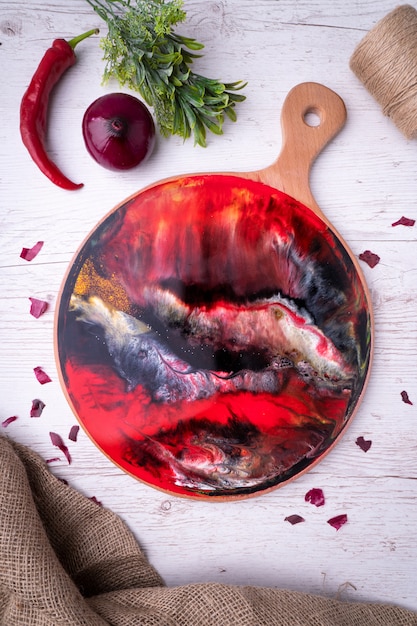 Nature morte, planche à découper avec un motif abstrait rouge, des légumes et des épices, couteau. Style Rostik.
