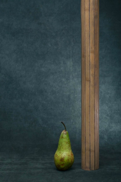 Nature morte avec une poire verte mûre et une figure en bois