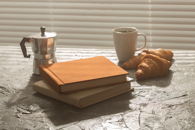 Nature morte pour une agréable tasse de café du matin et des croissants avec deux livres sur la table pour le déjeuner