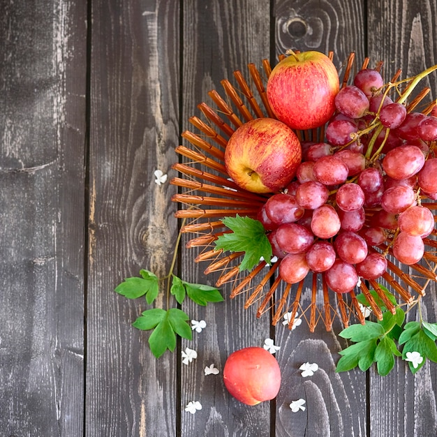 nature morte de raisins et de pommes dans un vase sur un fond en bois