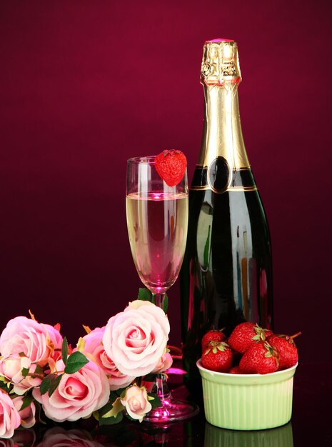 Nature morte romantique avec champagne, fraise et roses roses, sur fond de couleur sombre