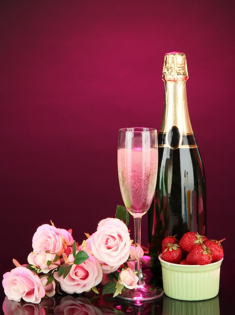 Nature morte romantique avec champagne, fraise et roses roses, sur fond de couleur sombre