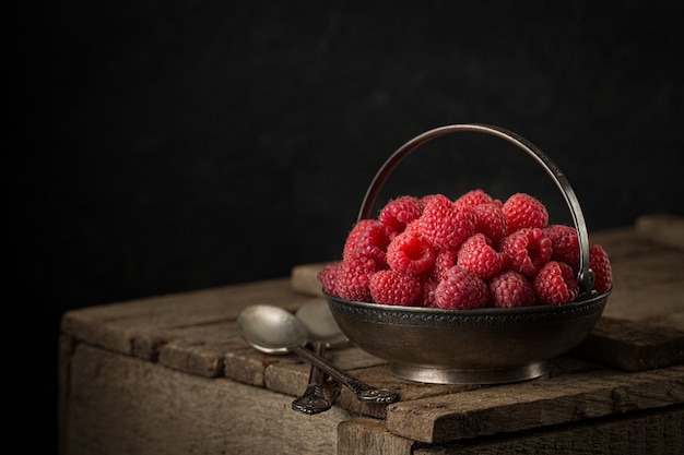 Nature morte rurale aux framboises sur une table rustique