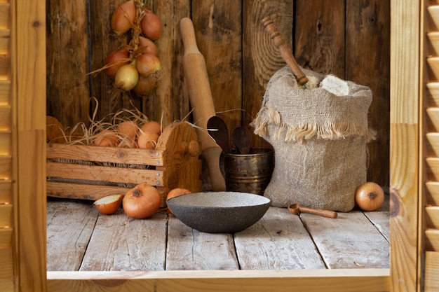 Nature morte rustique, farine, oignons, œufs et épices sur une table en bois.