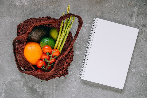 Nature morte de sac de shopping biodégradable brun avec des légumes crus sur fond gris