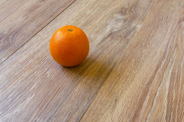 Nature morte - la seule orange sur une table en bois clair