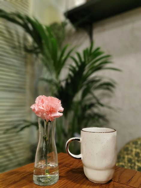 Nature morte avec une tasse de thé ou de café et une fleur d'oeillet dans un vase en verre