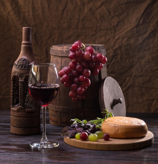 Nature morte avec verre de bouteille de vin et raisins sur fond de tonneau