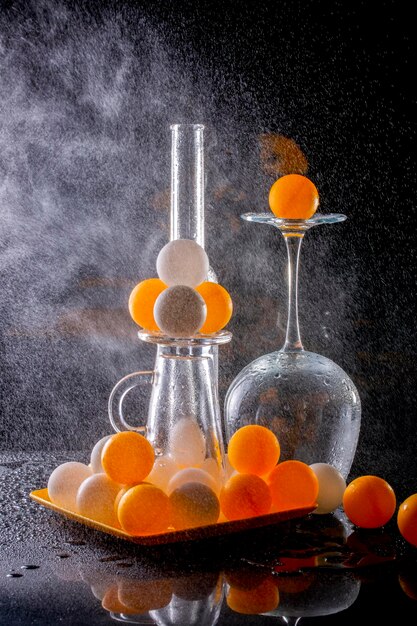 Nature morte avec des verres et des boules orange avec un jet d'eau