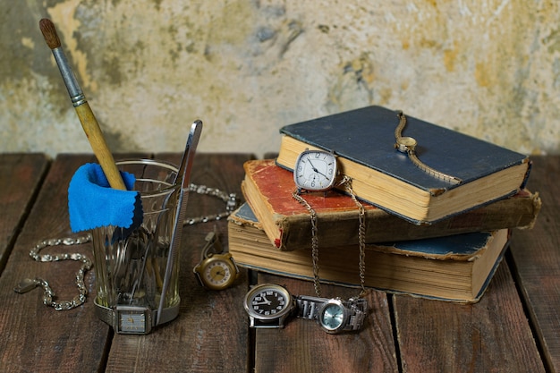 Nature morte avec de vieux outils en verre de livres d'horloges sur un fond en bois