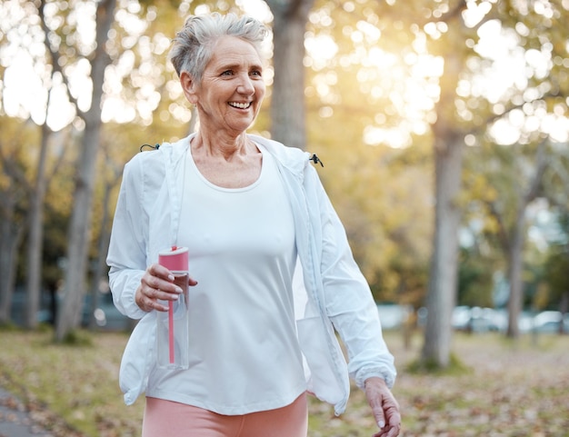 Nature de remise en forme et femme âgée avec une bouteille d'eau pour l'hydratation du bien-être et des minéraux pour marcher dans le parc Retraite de santé et femme âgée faisant de l'exercice et de l'entraînement cardio à l'extérieur