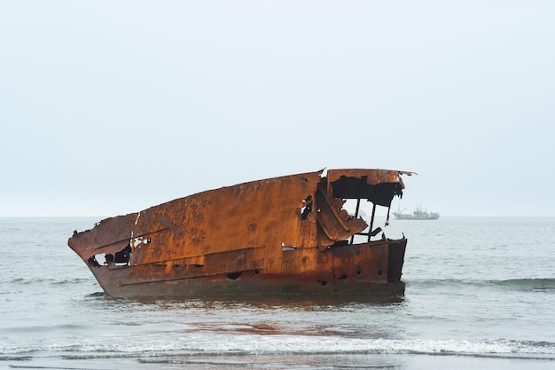 Naufrage rouillé contre un paysage marin brumeux avec un voilier