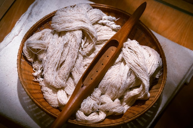 Navette en bois vintage et bobine sur fil de coton dans le métier à tisser Navette de tissage sur le tissu de coton Outil de tissage et tissu sur machine à tisser