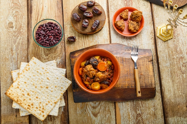 Navette de plat juif avec de la viande dans un plat en argile sur une table en bois près du matzo et des ingrédients. photo horizontale