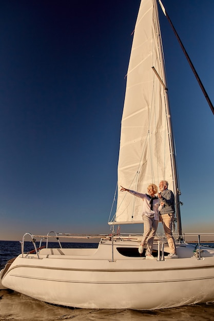 Naviguer autour du monde sur toute la longueur d'un couple de personnes âgées heureux debout sur le côté d'un voilier ou d'un yacht