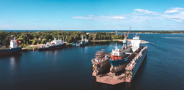 Navire en cale sèche flottante en réparation par sablage et peinture au chantier naval. Le cargo à la cale sèche flottante est en cours de rénovation