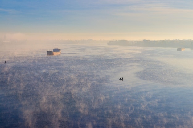 Navire industriel naviguant sur la rivière dans la brume le matin