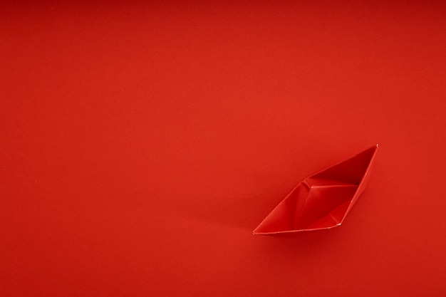 Navire de papier rouge sur fond rouge