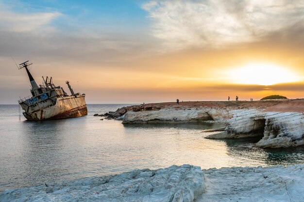 Navire rouillé abandonné échoué à terre dans les rayons du coucher du soleil au village de Peyia Paphos