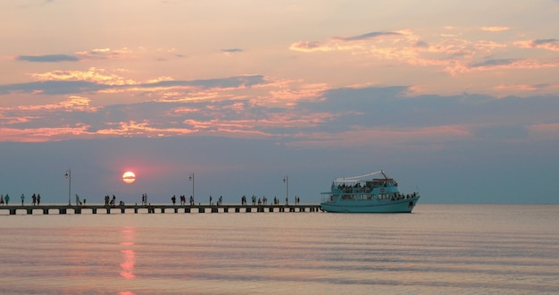 Navire touristique quittant la jetée au coucher du soleil