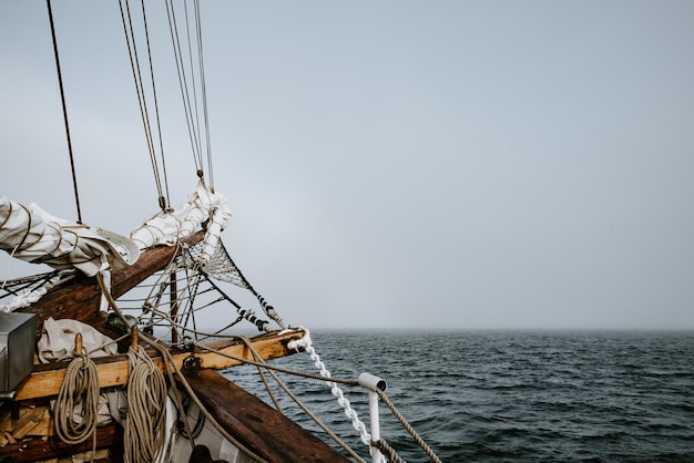 Photo navire à voile se déplaçant sur la mer par les montagnes contre le ciel