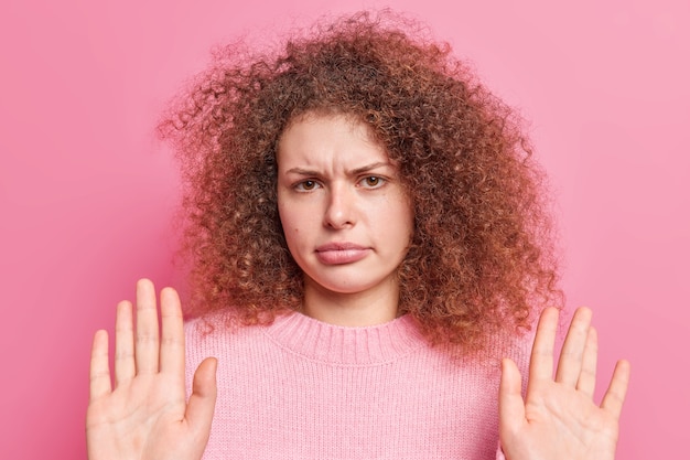 Ne m'implique pas là-dedans, je ne suis pas coupable. Une belle jeune femme aux cheveux bouclés insatisfaite lève les paumes vers ne veut pas avoir de problèmes avec une expression mécontente. Va-t-en