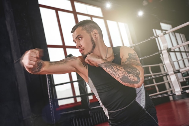 Né pour combattre l'homme fort dans la boxe de vêtements de sport avec un crochet de lancement d'athlète confiant d'ombre