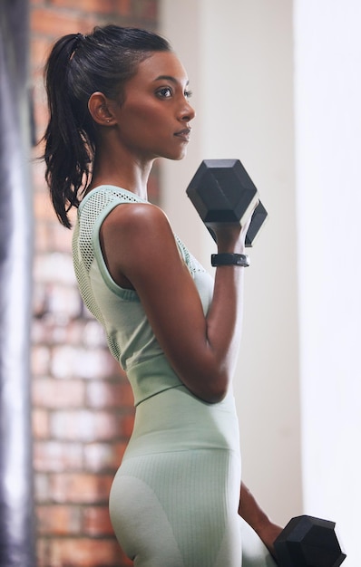 Ne soyez pas moyen, soyez sauvage Photo d'une jeune femme qui s'entraîne avec un haltère dans une salle de sport