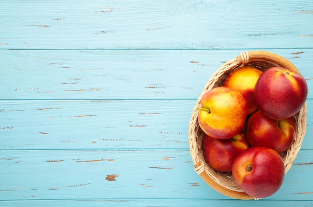 Nectarines dans un panier sur bois bleu avec copie espace