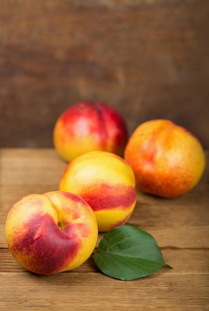 Nectarines fraîches avec des feuilles sur fond de bois