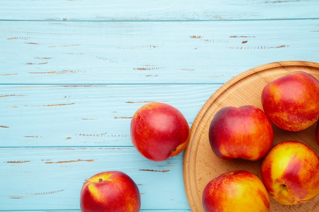 Nectarines sur une planche à découper sur bleu.