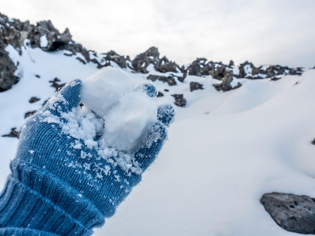 Neige blanche dans une main gantée bleue en hiver